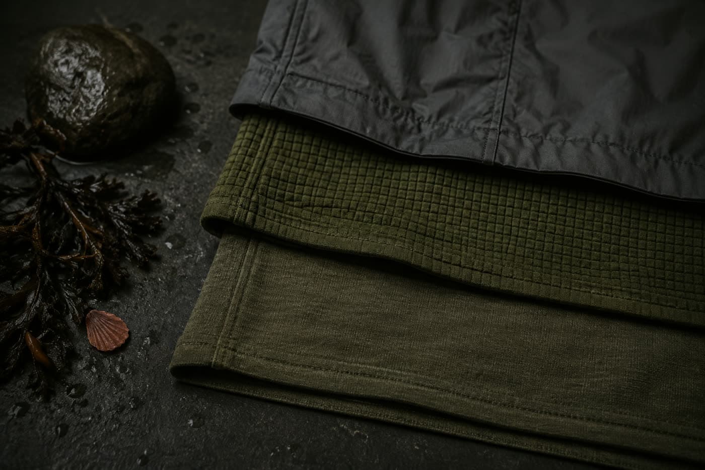 Three fabrics laid in overlapping bands: fine merino knit, grid fleece, and a matte woven shell